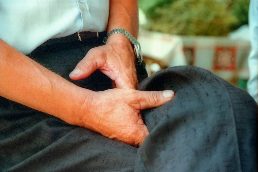 Manos evaluando la rodilla de un paciente sentado